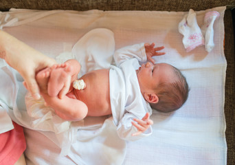 Mom giving newborn baby a diaper change at home