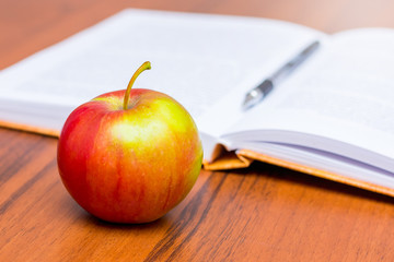 Red mature juicy apple on the background of an open book_