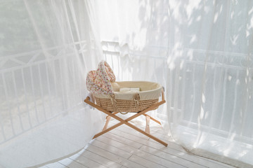 Retro baby crib on terrace rounded with curtain at sunny day