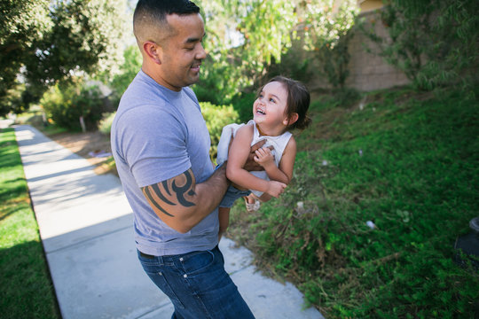 Young dad playing with child outside in suburb neighborhood
