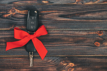 Close-up view of car keys with red bow as present on wooden vintage background