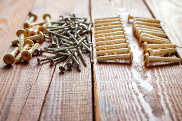 Dowels and screws closeup on a wooden background. Selective focus.