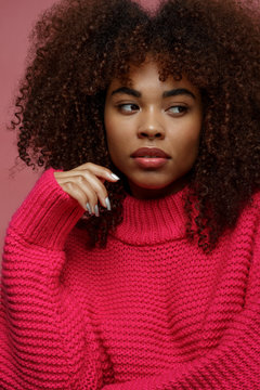 Portrait of a young African American afro woman in pink studio