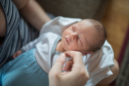 Closeup image of mother's hands holding head of sleeping one wek old baby girl