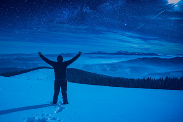 Hiker with raised hands standing on a snowy hill