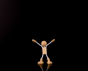 Wooden Stick Figure arms up, isolated on black background, copy space