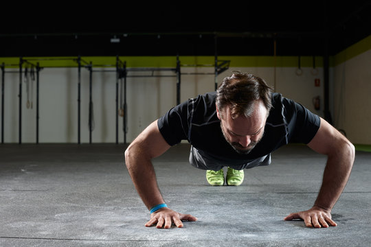 Mature male exercising push ups in a gym or fitness club