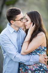 Naklejka premium Romantic summer love story on a sunset in mountains. Young girl and boy in love. pregnant women