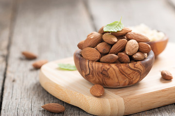 Almonds nuts in wooden bowl on rustic table.