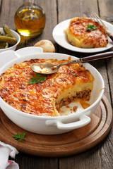 Shepherd's pie, traditional British dish with minced meat and mashed potato on rustic wooden table.