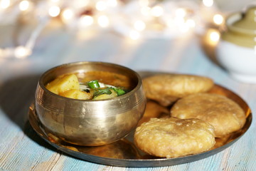 A plate of Khasta Kachauri with a bowl of spicy and tangy Potato sabji or curry.