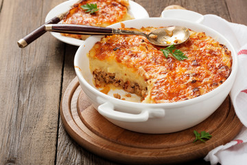 Shepherd's pie, traditional British dish with minced meat and mashed potato on rustic wooden table.