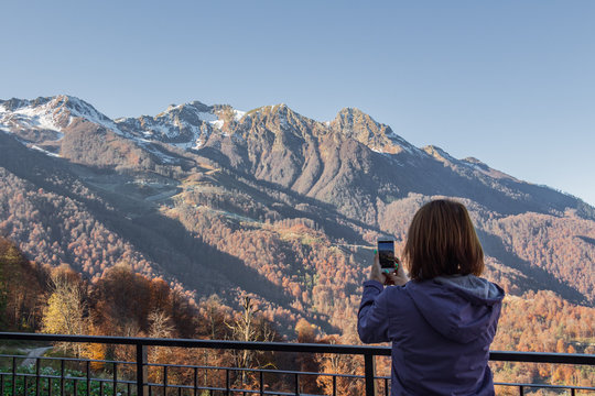 Woman with mobile phone in mountains. Rosa Khutor.