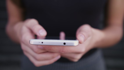 Business woman type message, using smartphone on street, closeup shot of mobile device in hands, blurred background