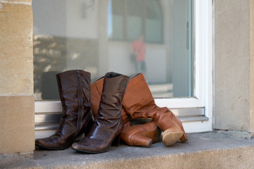 Old boots thrown away on a window sill. Female boots with heels.