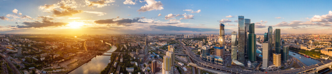 high-rise buildings and transport of metropolis, traffic and blurry lights of cars on multi-lane highways and road junction at sunset in Moscow