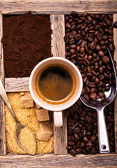 In the rustic wooden container, with a top view, a cup of espresso, raw cane sugar and toasted...