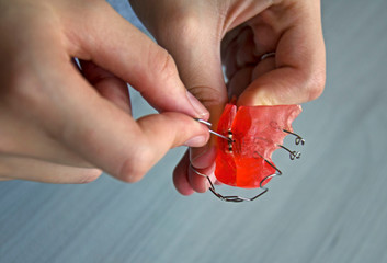 The girl shows how to properly tighten the plate for the teeth.