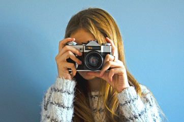 A girl is taking pictures on an old camera. Vintage camera on film