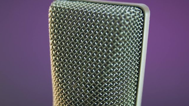 Vocal condenser studio microphone rotating. Dark background.