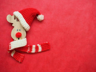 Cute wooden deer in red hat of Santa Claus. Funny Christmas background