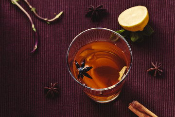 Oriental tea on a brown cloth Mat with spices and lemon. Lemon, mint, ginger, cinnamon.