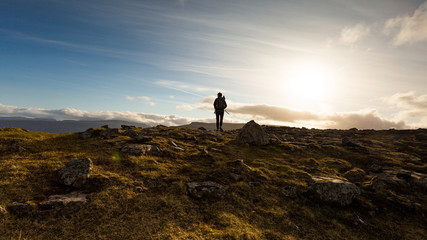 Man exploring the highlands of Faroe Islands on a beautiful sunny day of summer