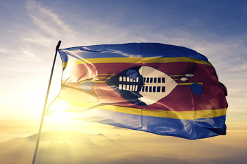 Swaziland Kingdom of eSwatini flag textile cloth fabric waving on the top sunrise mist fog