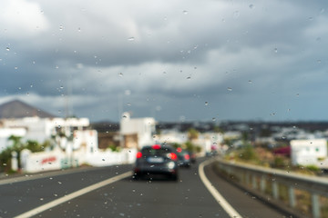 Water droplets on a windshield with a blurred traffic background.