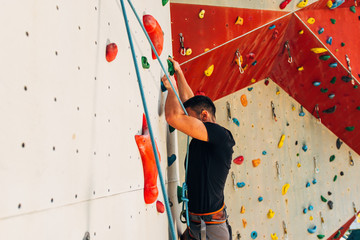 Muscular man climbing on a big wall