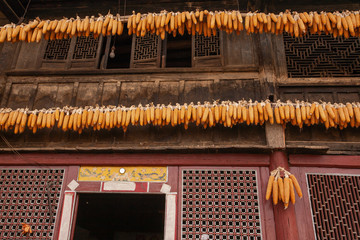 Corn cob hanging on wooden lintel of ancient Chinese house.