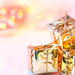 Happy Christmas, New Year, gifts in gold boxes on a background of pink and yellow bokeh.