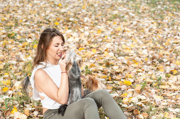 Beautiful young girl with her Yorkshire terrier dog puppy enjoying and playing in the autumn day in the park selective focus