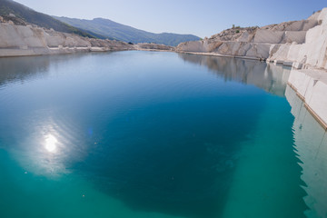 Marble quarry landscape in the mountains with a turquoise lake water