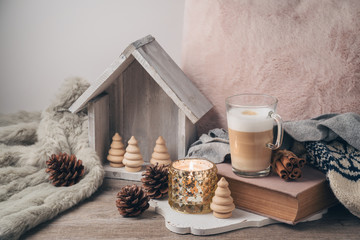 Hygge Scandinavian style concept with latte macchiato coffee cup, candles and book.