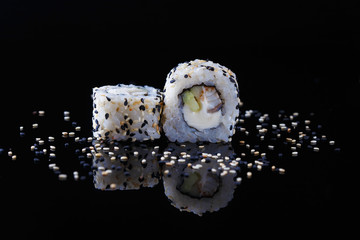 delicious sushi roll with fish and sesame on a black background with reflection Menu and restaurant concept