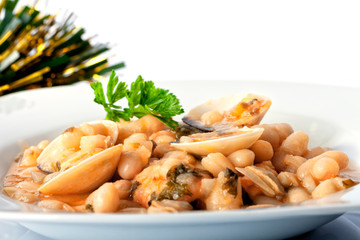 A plate of white beans with clams and prawns and Christmas decoration isolated