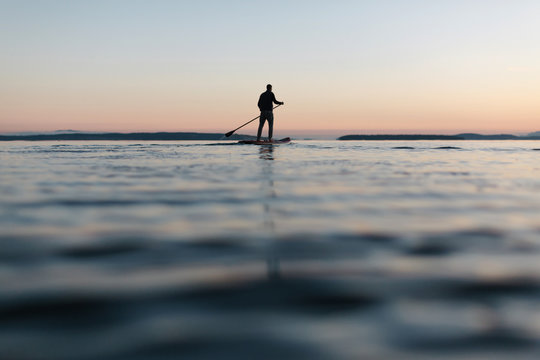 Couple stand up paddle boarding together at sunrise