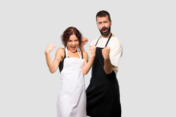 Couple of cooks celebrating a victory and happy for having won a prize on grey background