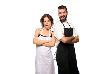Couple of cooks showing tongue at the camera having funny look on isolated white background