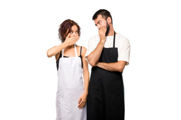Fototapeta premium Couple of cooks covering mouth with hands for saying something i on isolated white background