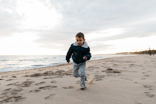 Little boy running on sandy shoreline