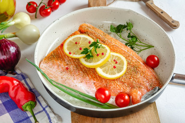 Fresh salmon in a pan with lemon and cherry tomatoes ready to cooking.