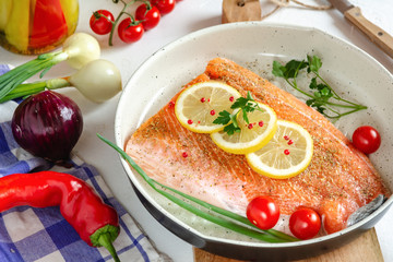 Fresh salmon in a pan with lemon and cherry tomatoes ready to cooking.