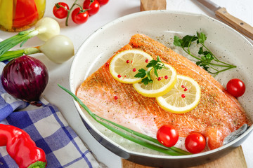 Fresh salmon in a pan with lemon and cherry tomatoes ready to cooking.