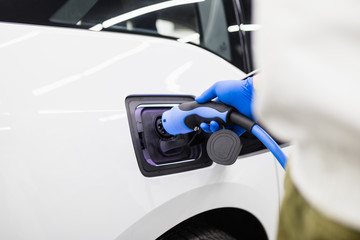 Charging cable plugged into electric car at charging station.