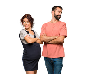 Couple with pregnant woman looking over the shoulder with a smile on isolated white background