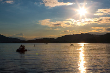 placid lake with people on a pedalo floating in sunset