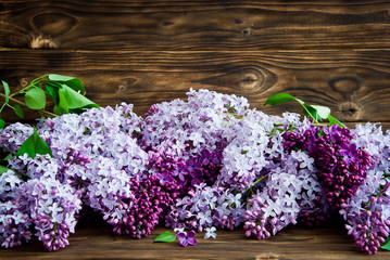 Purple flowers of lilac with leaves on a wooden background