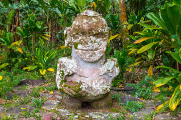Smiling tiki. Carved stone tiki - Polynesian sacred idol statue hidden in jungle. Raivavae island,...